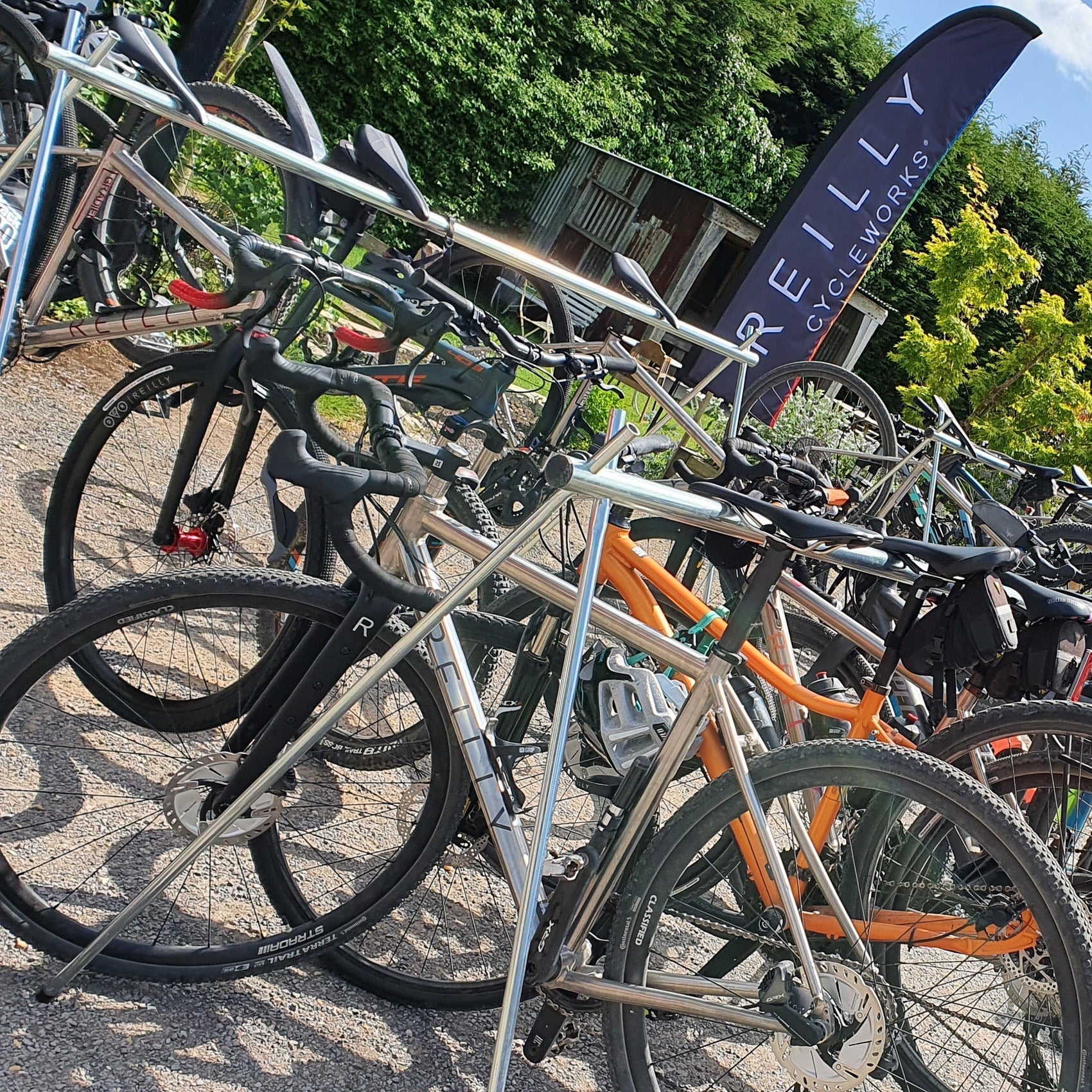 multiple bikes being held up by a metal frame, with a 'reilly cycleworks' banner in the background.
