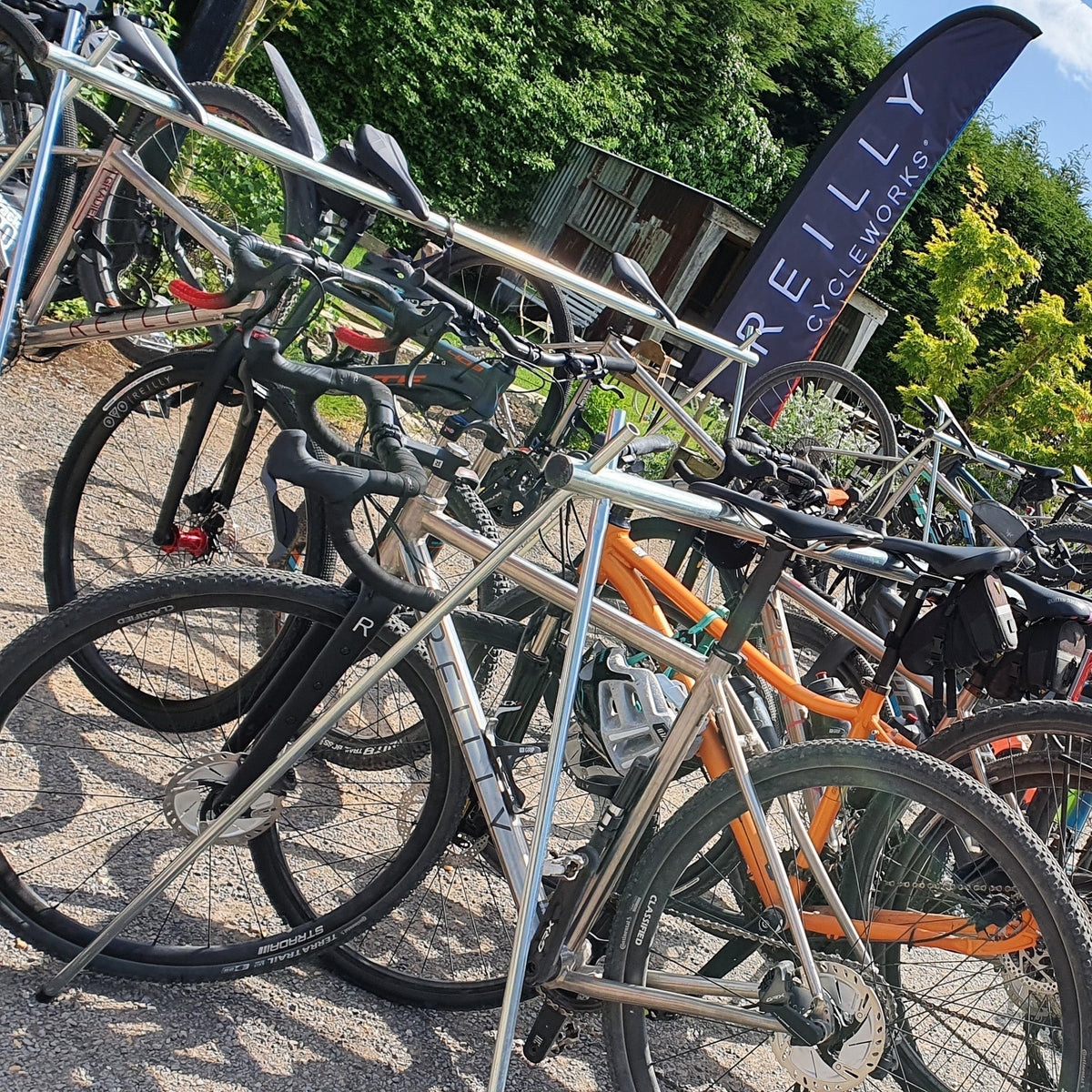 multiple bikes being held up by a metal frame, with a 'reilly cycleworks' banner in the background.