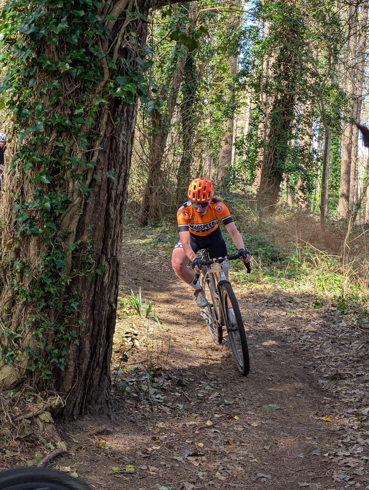 A cyclist racing on a gravel path leaning into a corner wearing orange 