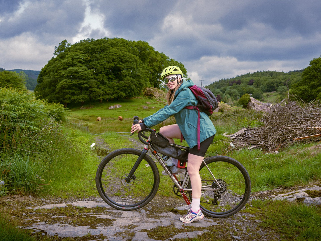 Woman with a bicycle on a rural path with greenery and cloudy sky