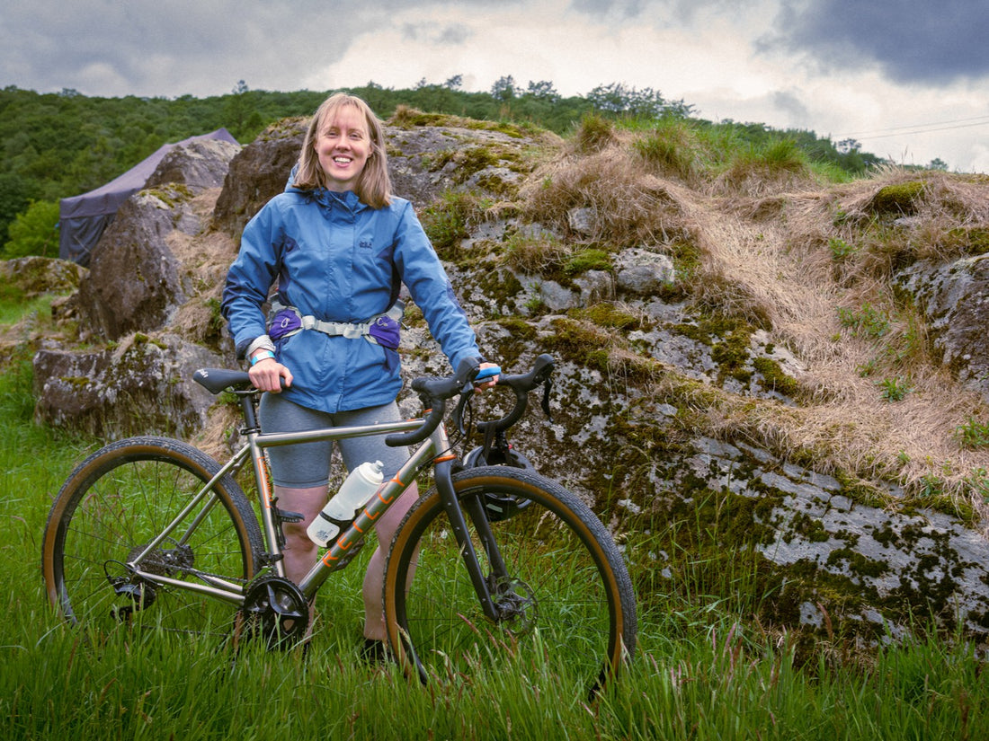 Person with a bicycle in a natural landscape with rocks and grass.