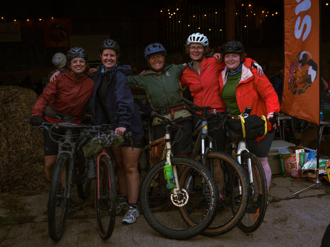 Five people with bicycles posing together in a dark indoor setting.