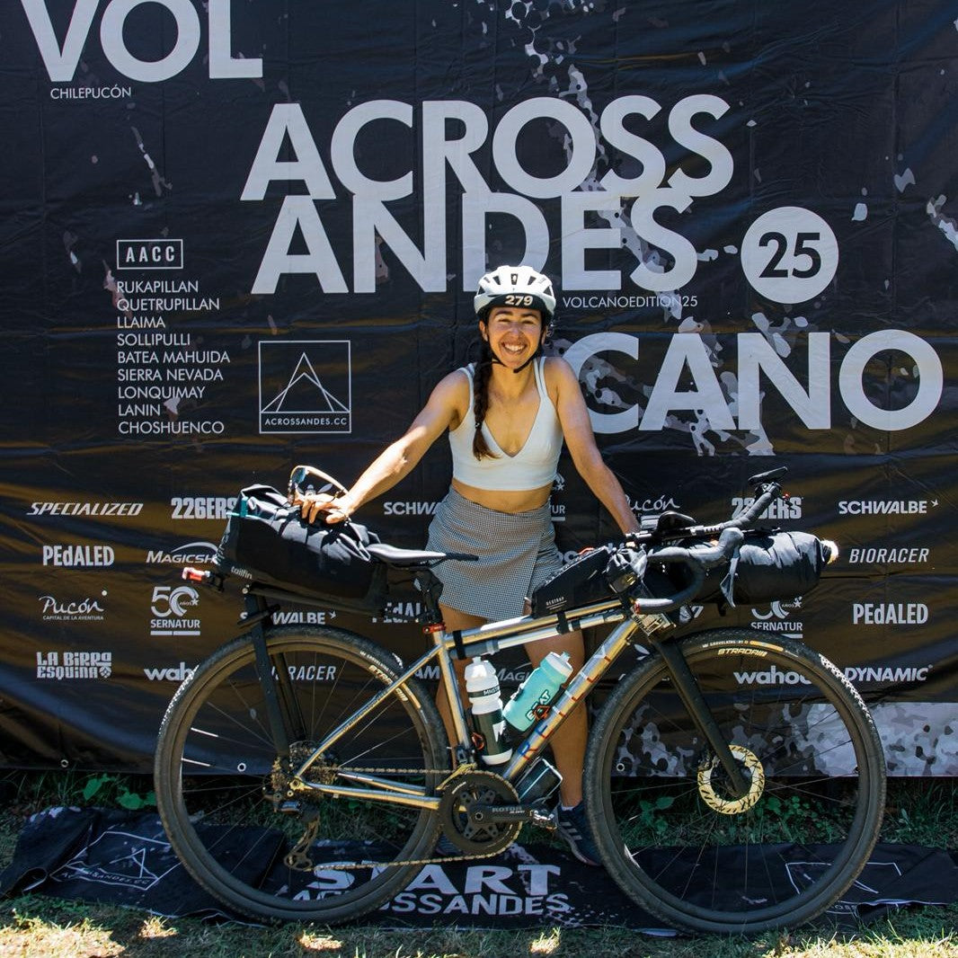 A woman stands with her bike infront of Across Andes banner.