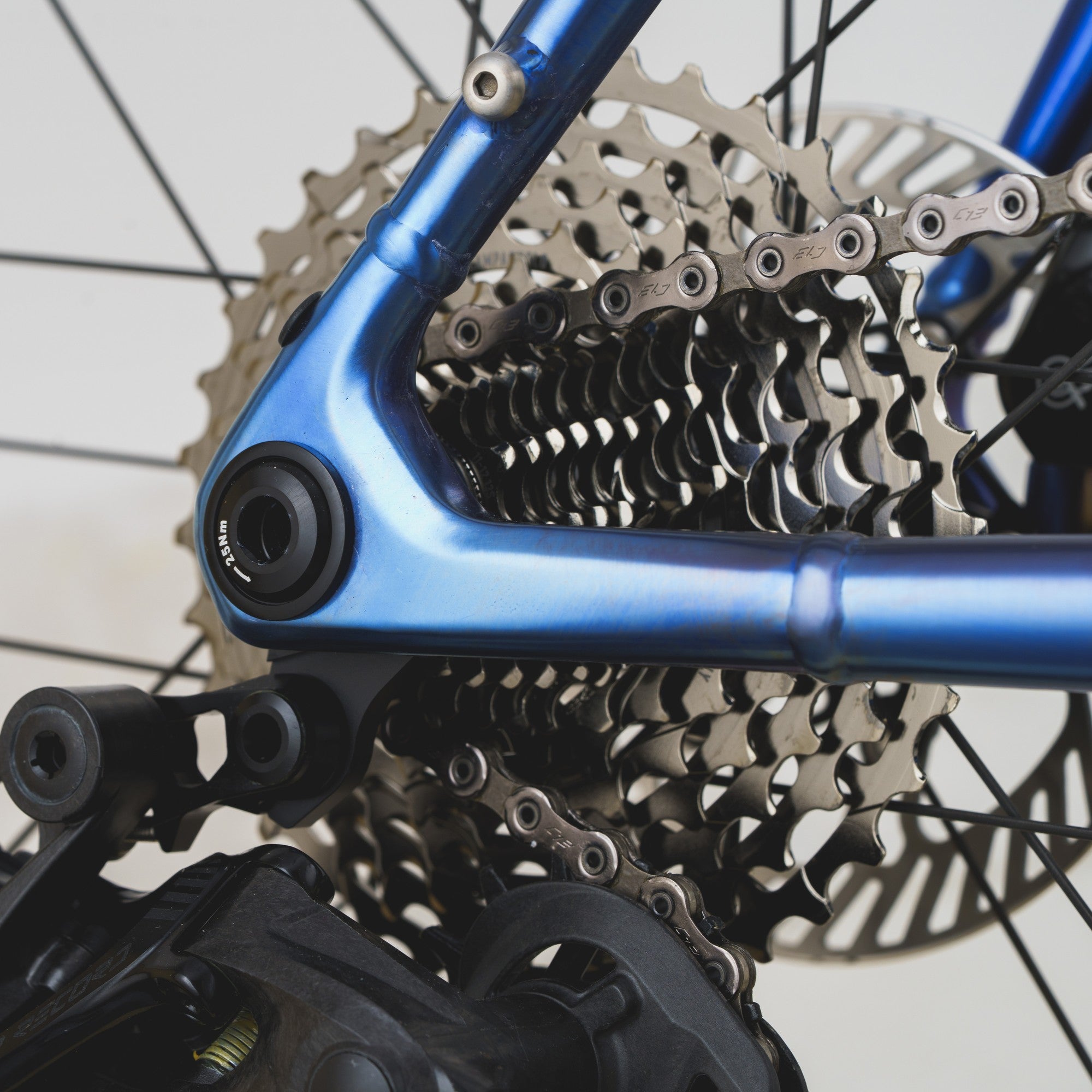 Close-up of a bicycle rear cassette, chainring, and blue frame component with no person or environment visible.