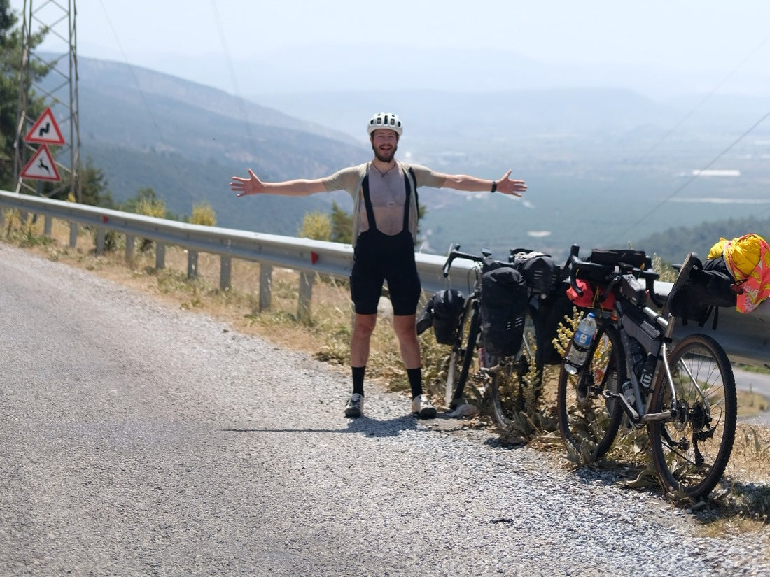 A cyclist has his arms outstretched on a mountain path.