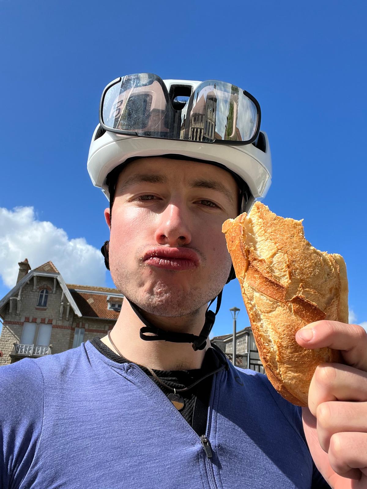 A cyclist enjoys a baguette.