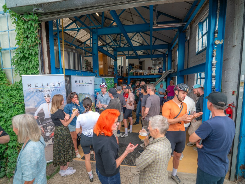 Group of people gathered outside a building with promotional banners for Reilly Titanium bikes