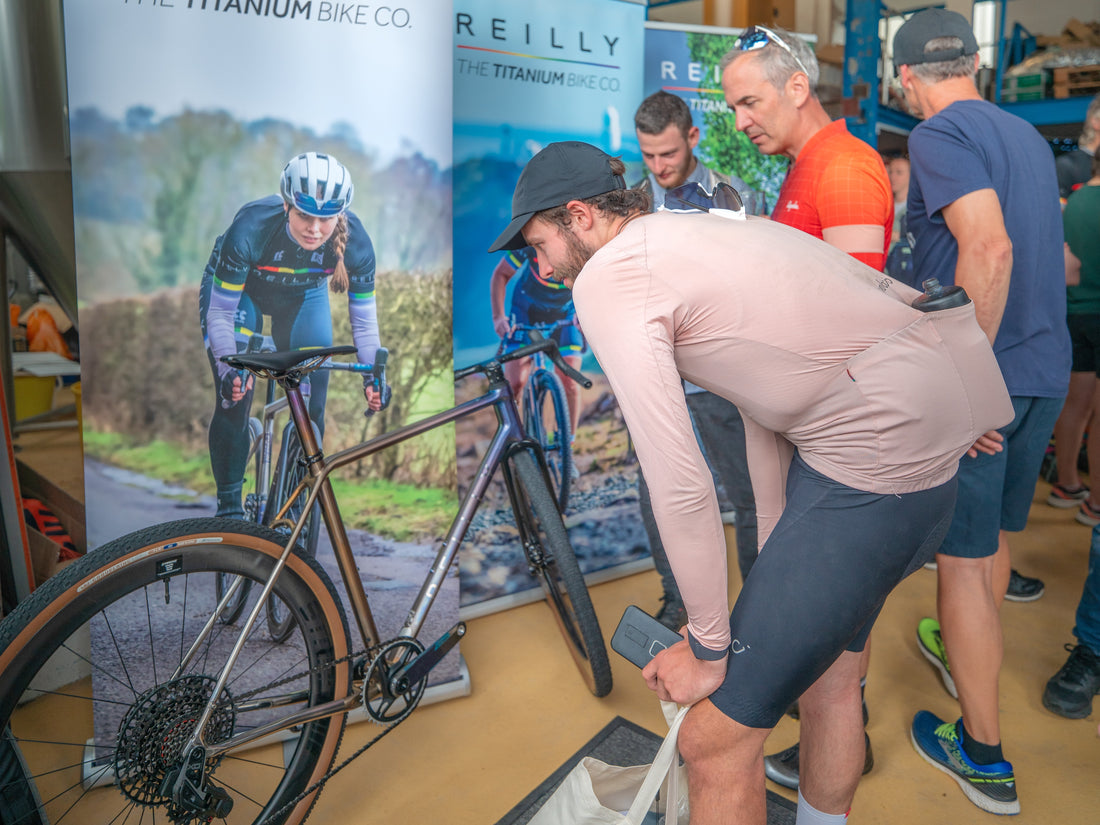 Person inspecting a bicycle with Reilly Titanium banners in the background