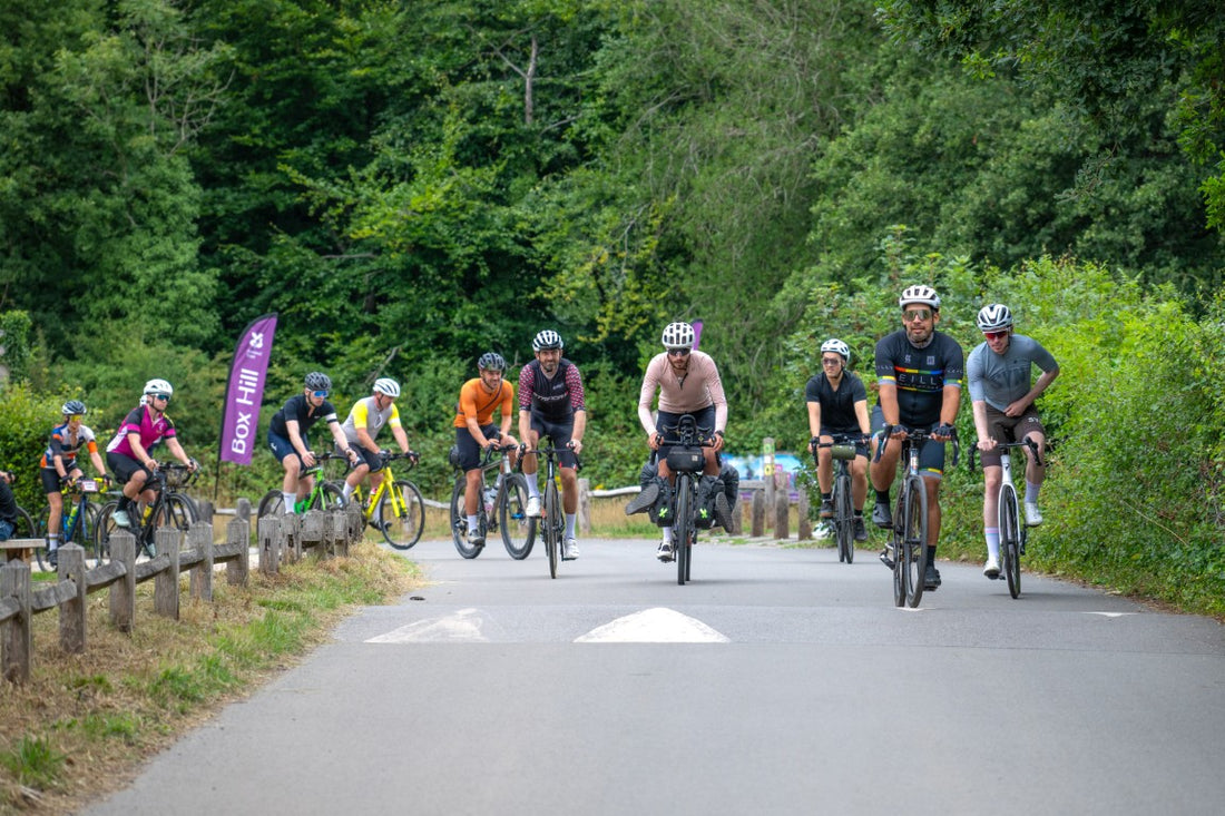 Group of cyclists riding on a road surrounded by trees