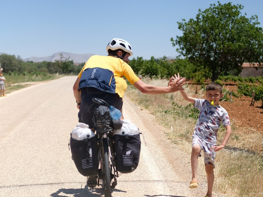 A cyclist high fives a small boy.