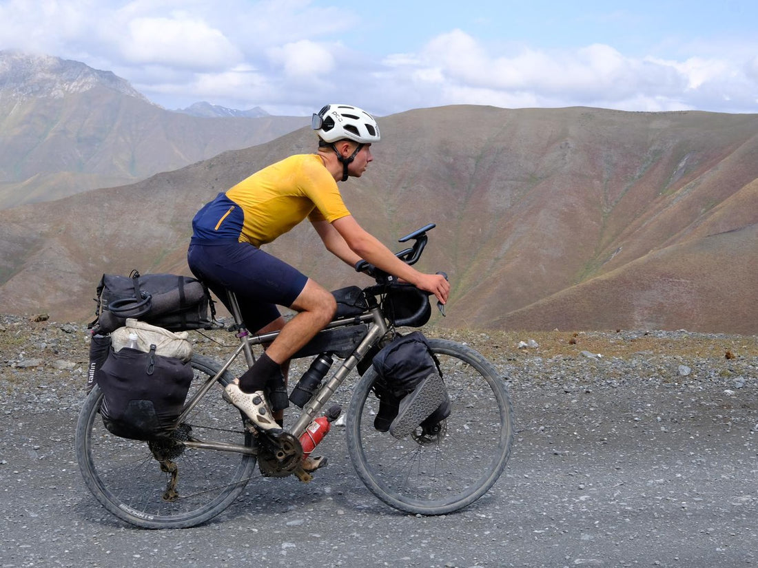 Side on image of a cyclist with a bike laden with bags.