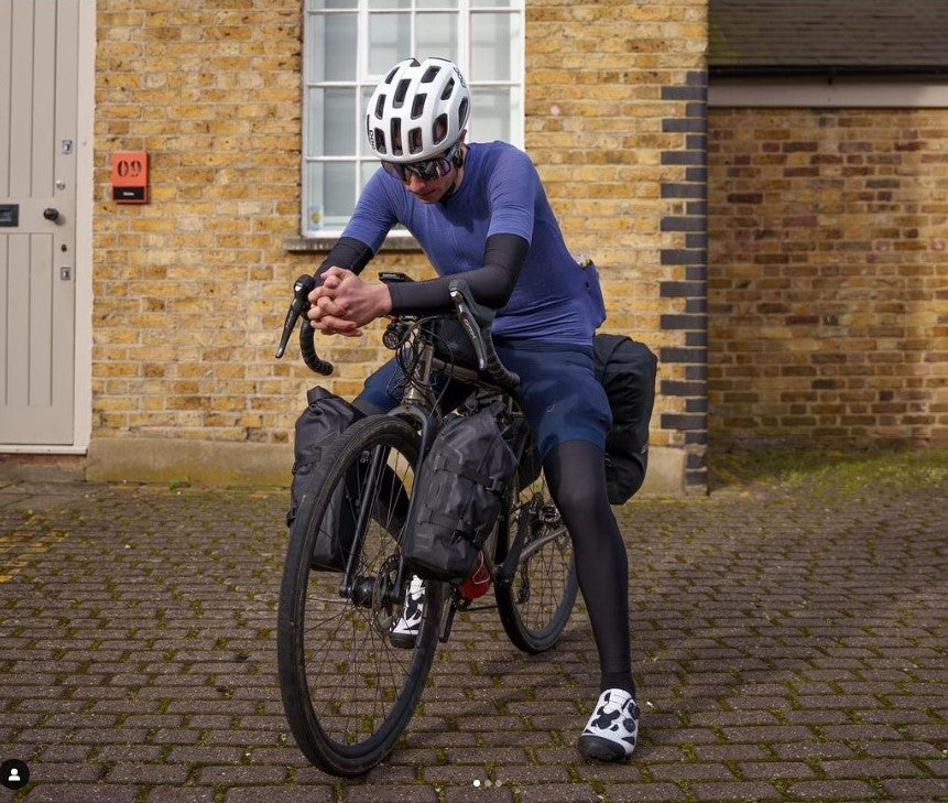A cyclist straddles his bike with many bikepacking bags attached.