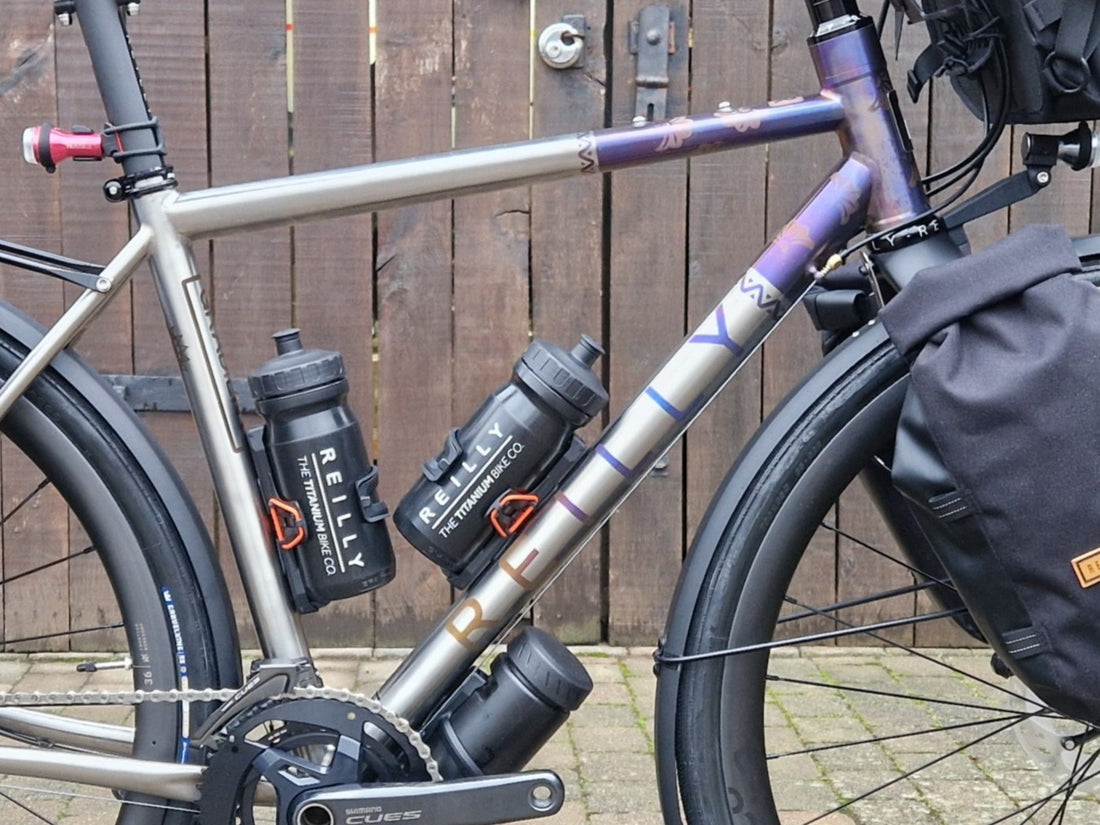Bicycle with water bottles and a bag against a wooden fence.
