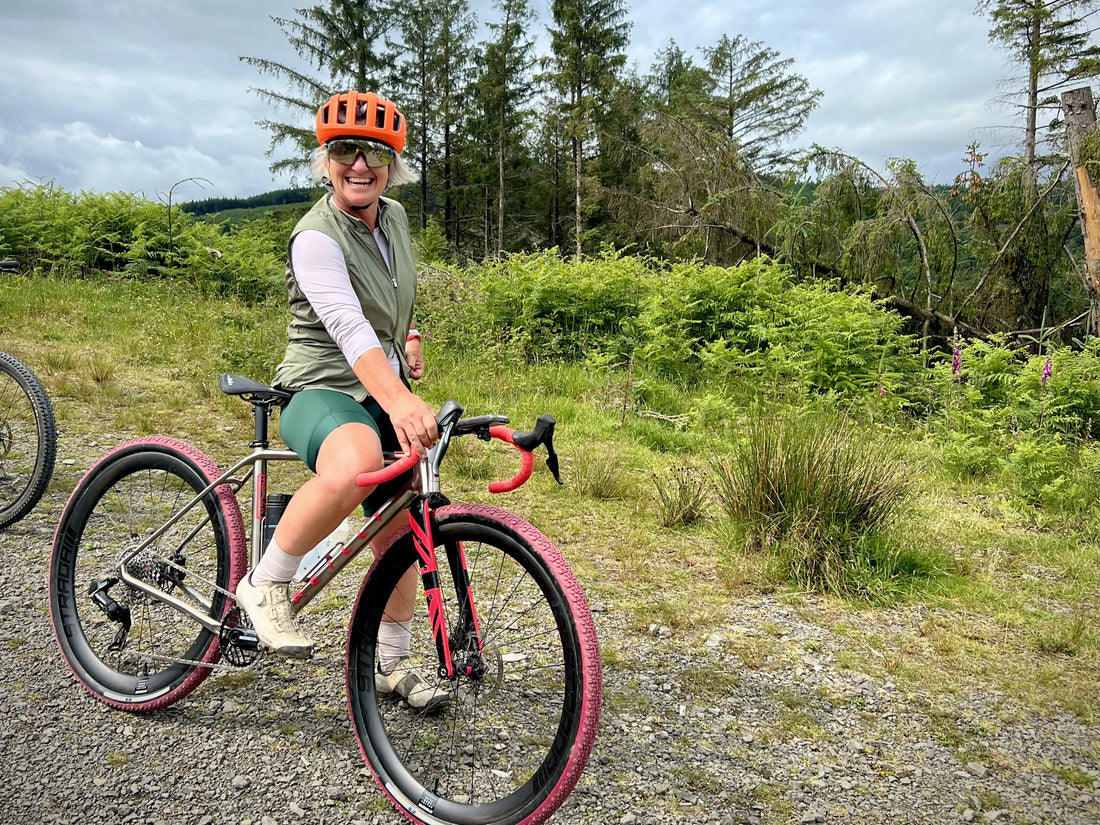 Person smilling, with a bicycle in a forested area