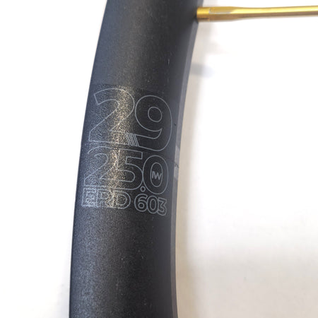 Close-up of a bicycle rim with specifications engraved on a white background