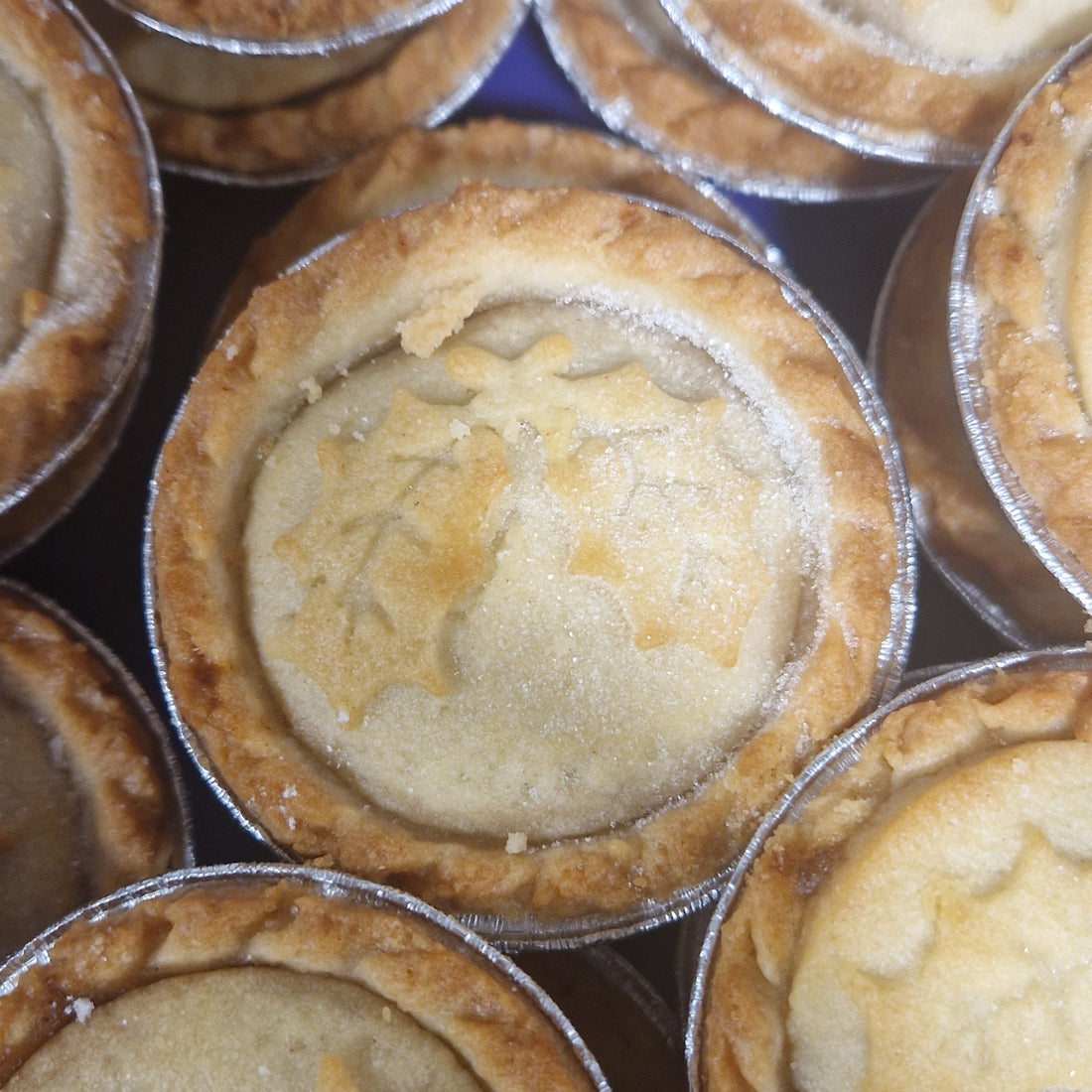 Close-up of small pies in metal tins arranged in a grid pattern.