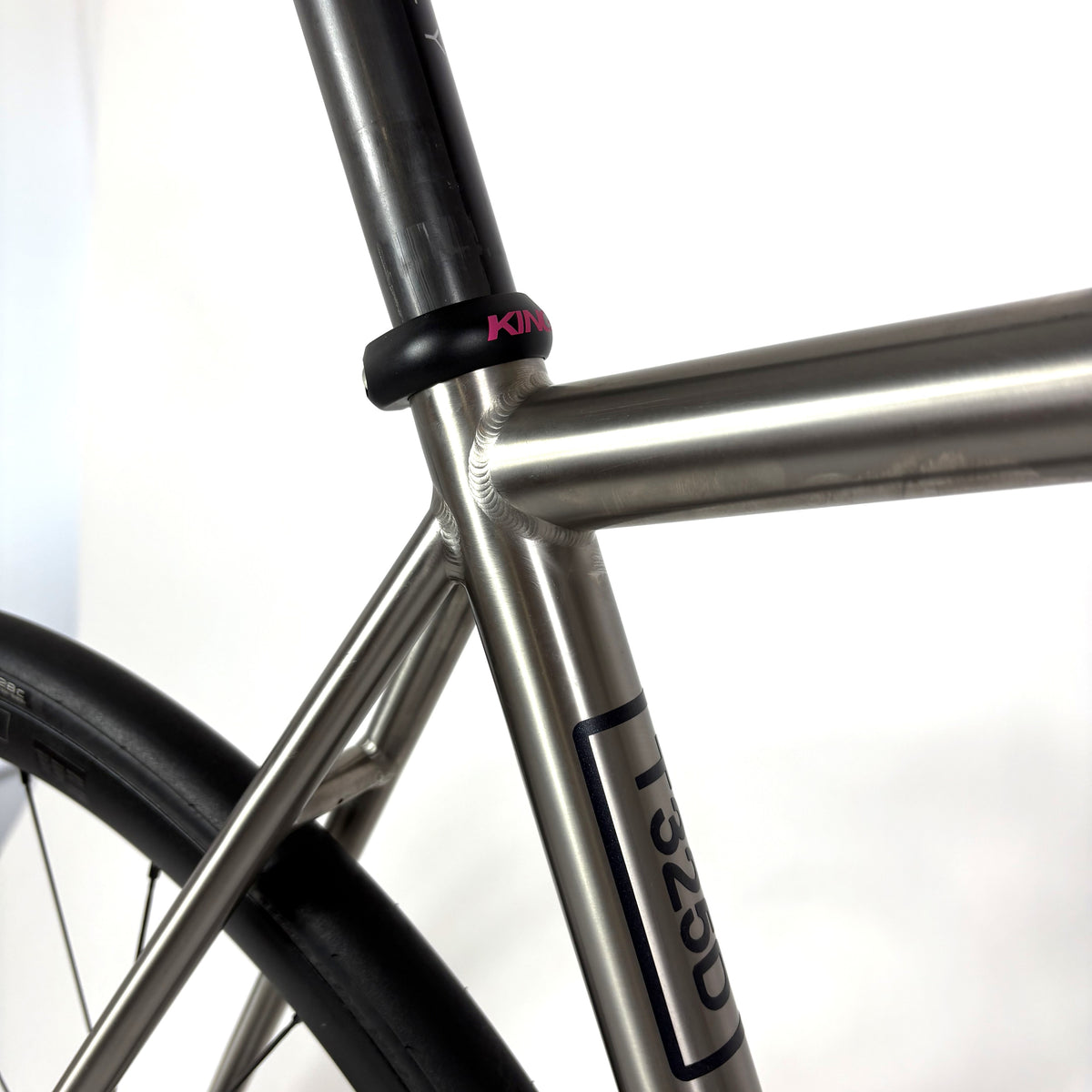 Close-up of a bicycle frame featuring a titanium frame and a black seat clamp