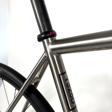 Close-up of a bicycle frame featuring a titanium frame and a black seat clamp