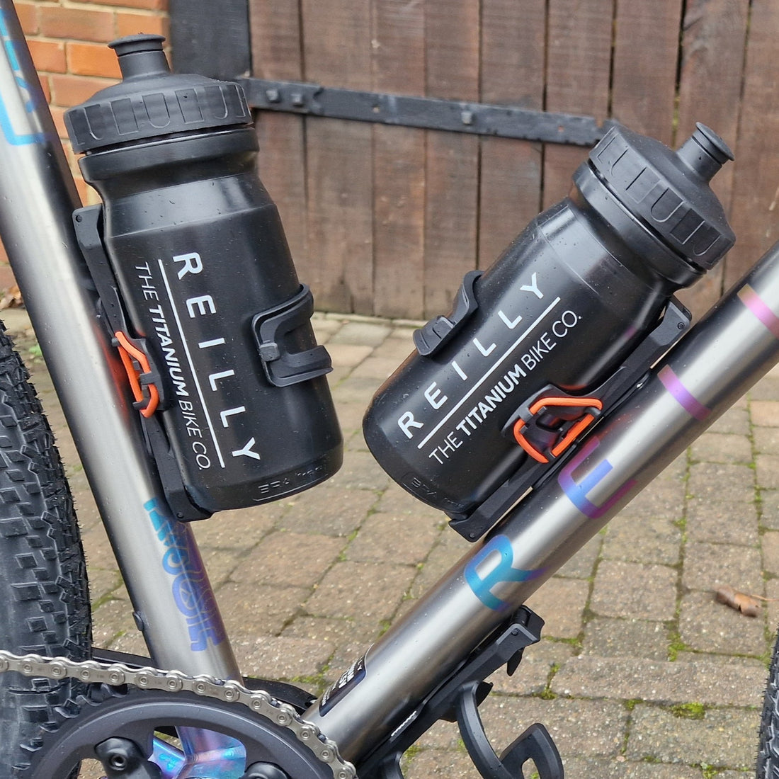Two black Reilly Titanium Bike Co. water bottles attached to a bicycle frame.