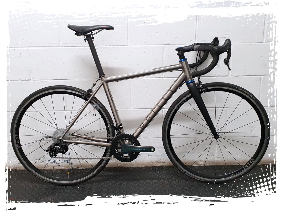 silver bike photographed in front of a white wall.