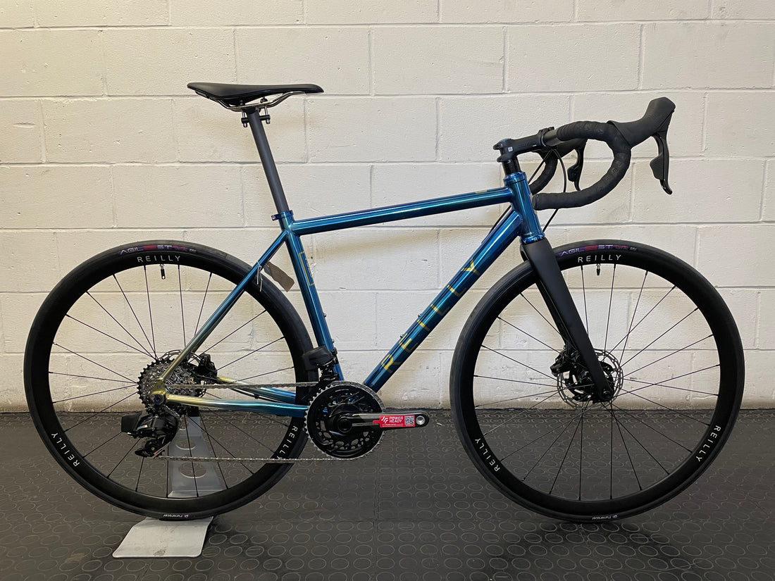 custom Reilly titanium blue bike in front of a white wall