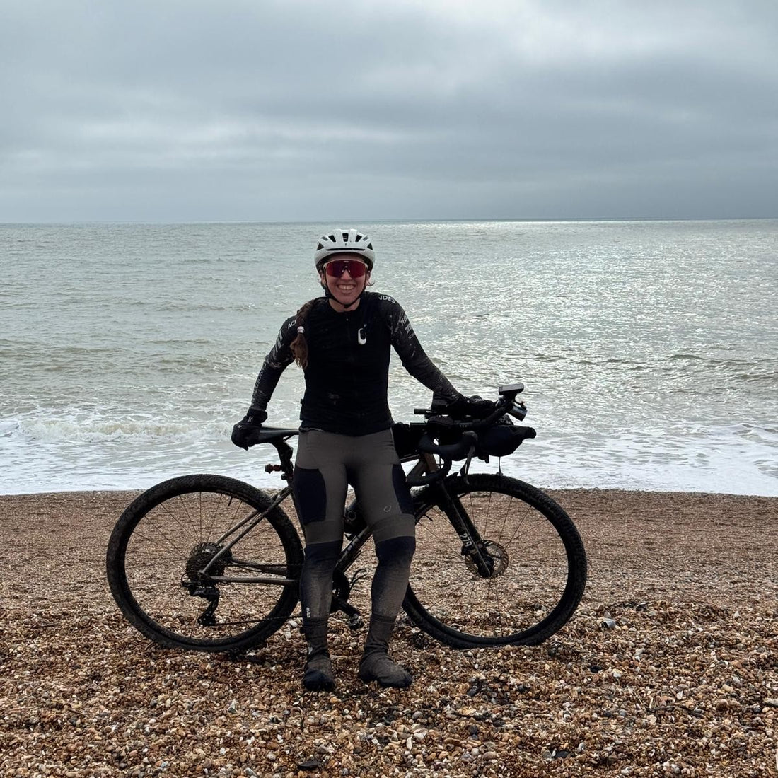 A cyclist on a British beach with her bike.