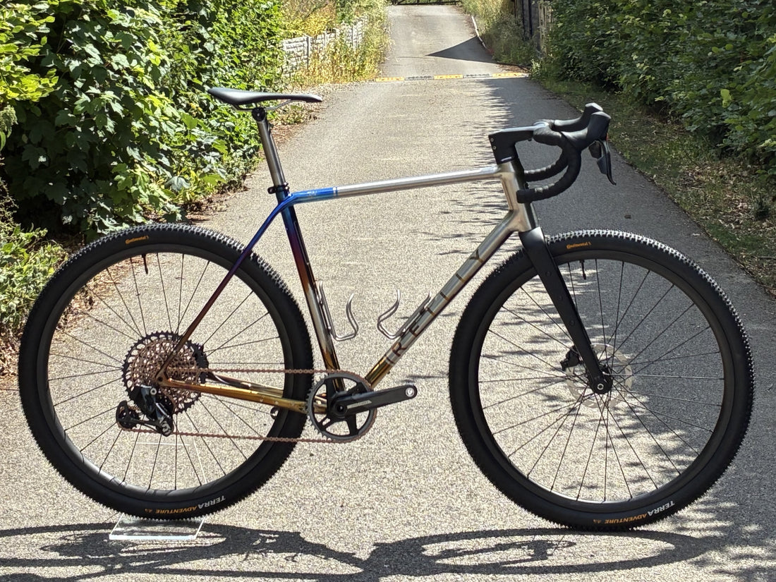 Titanium Bicycle on a paved road with greenery on either side