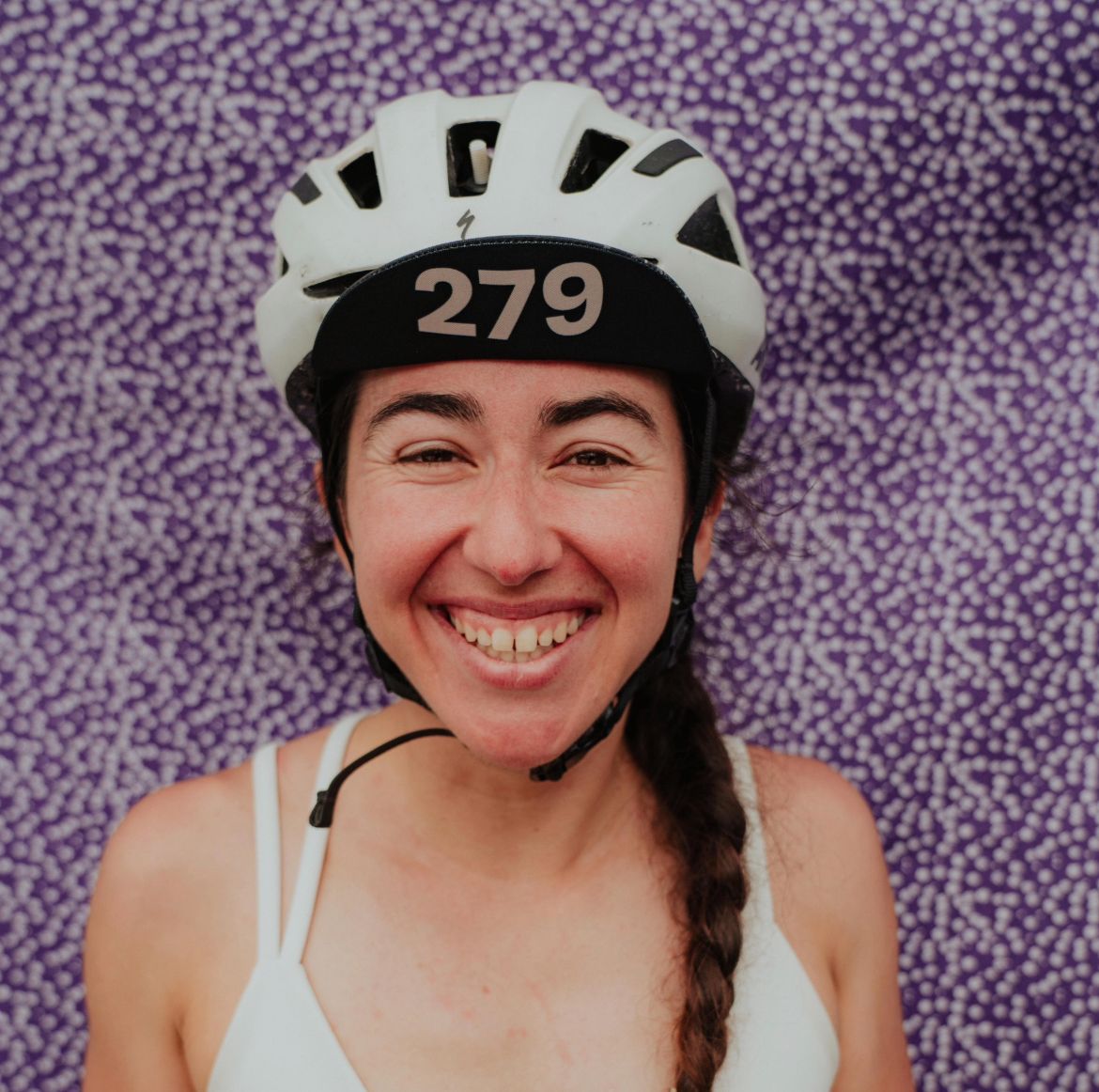 Female wearing a white helmet  on a purple patterned background