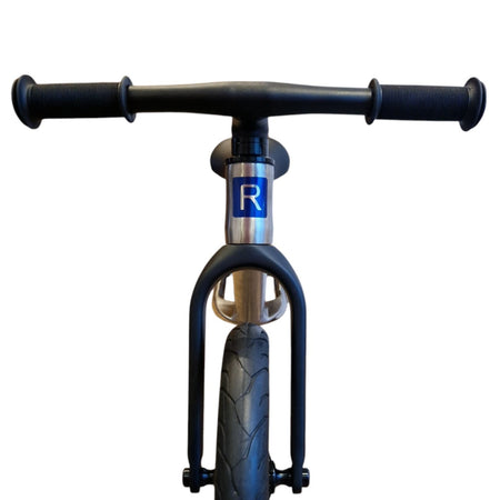 The front view of  titanium balance bike on white background.