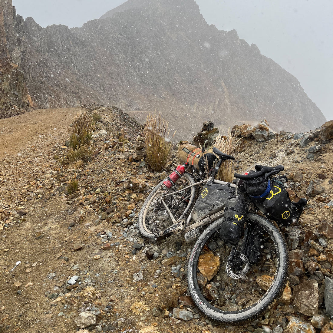 a bike layed on the side of a mountain with hail falling onto it.