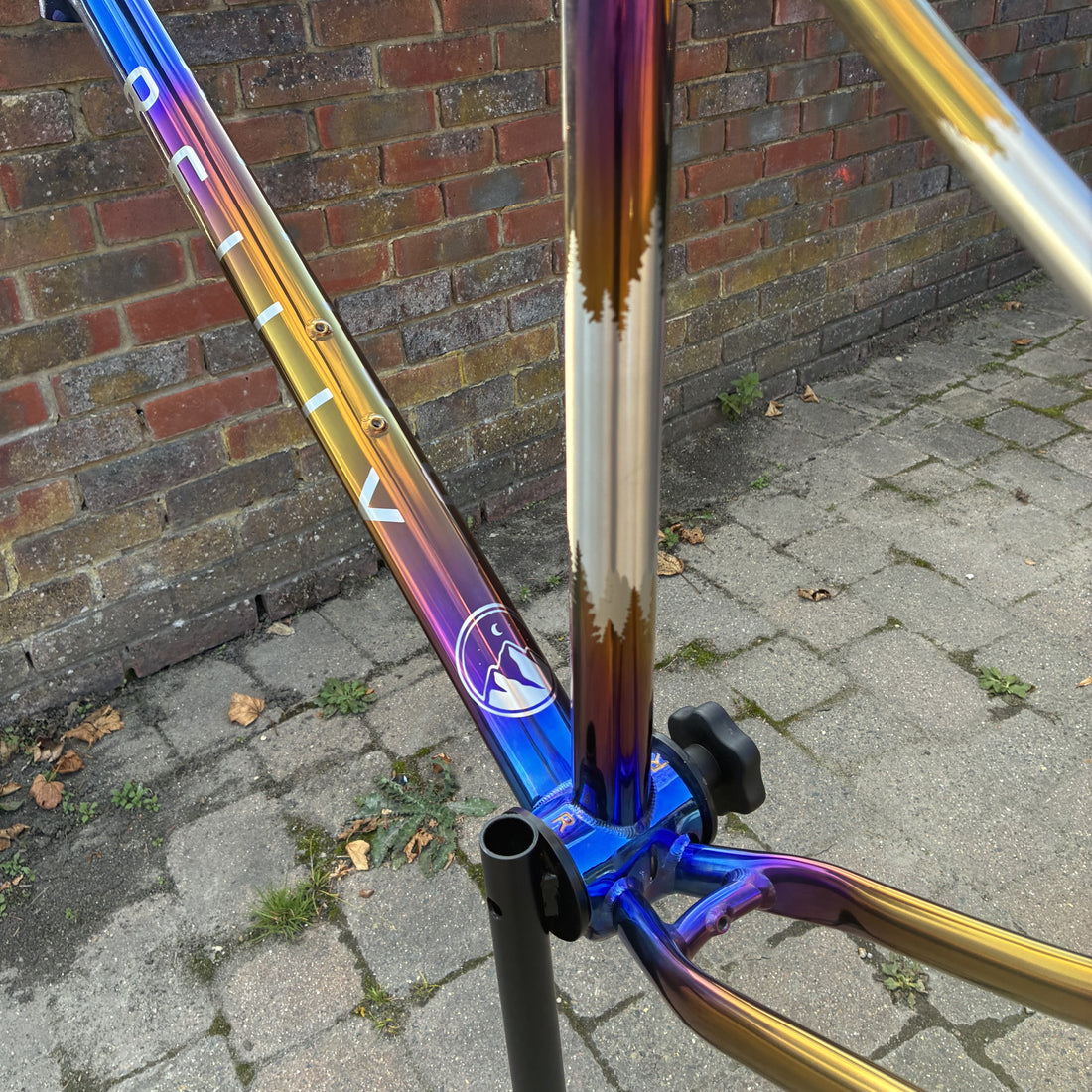Multicolored bicycle frame leaning against a brick wall on a pavement.