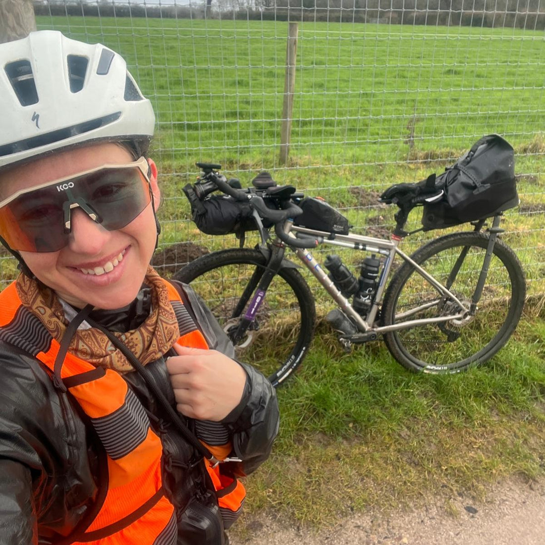 A woman by her bike with bags.