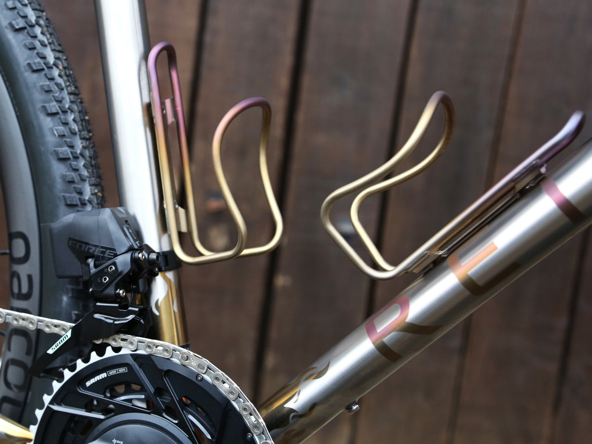 Close-up of a bicycle with gold water bottle holders on a wooden background