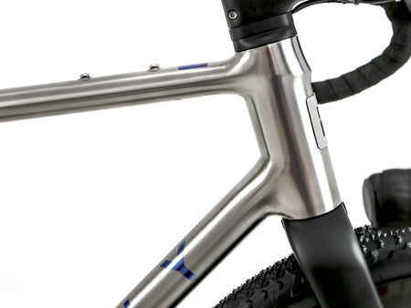 Close-up of a metallic silver bicycle frame with black handlebar tape and a black tire, shown against a white background.