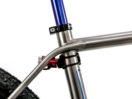 Close-up of a bicycle frame showing the head tube, black seat post clamp, red rear light, and part of a black tire against a white background.