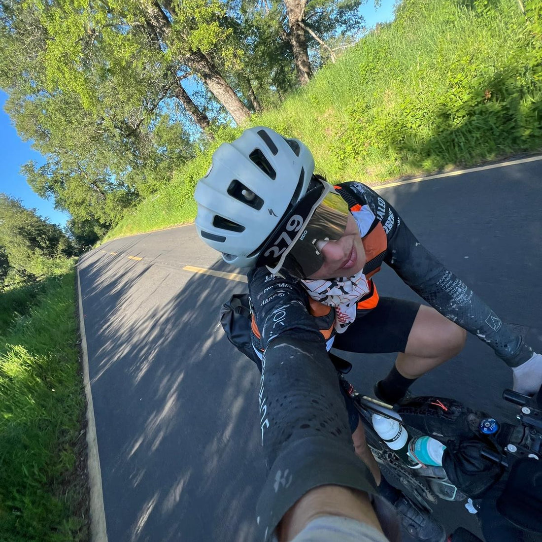 A female cyclist on tarmac road cycles along.