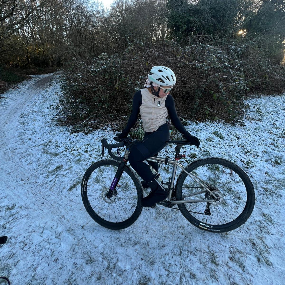 Female cyclist in snow looks at ther bike.