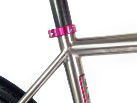 Pink seat tube clamp on a titanium bike frame 