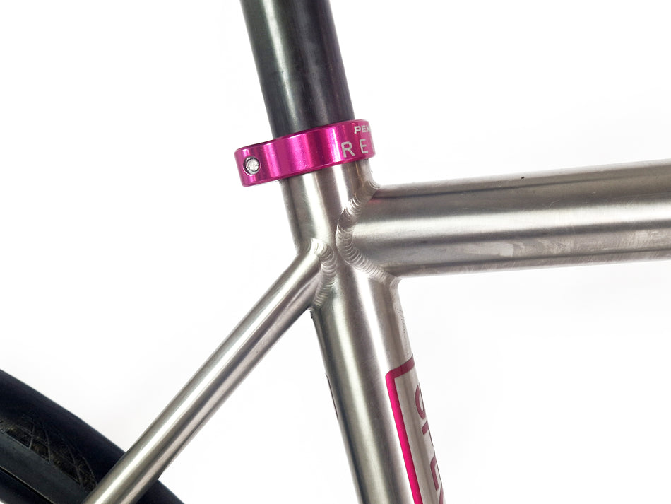 Pink seat tube clamp on a titanium bike frame 