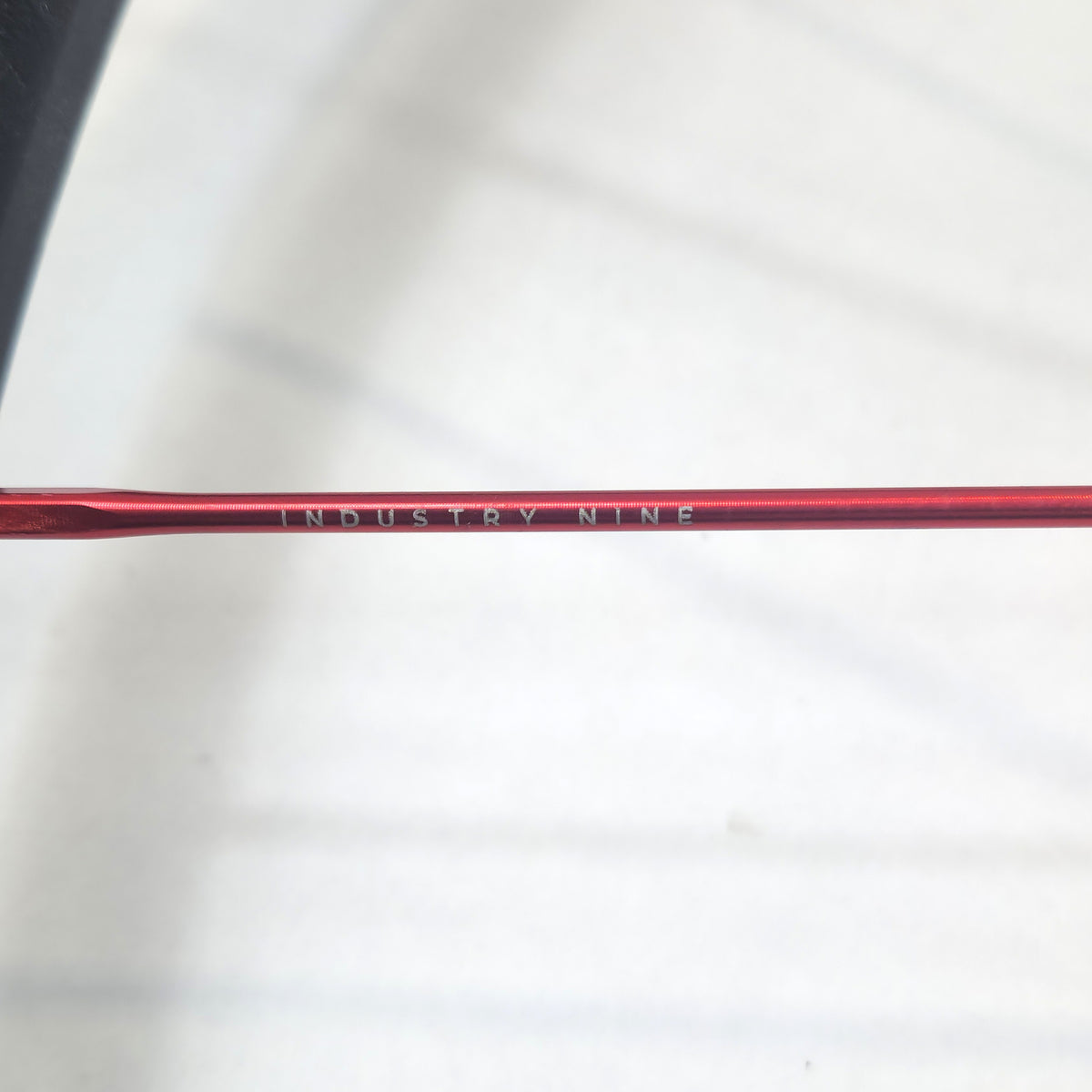 Close-up of a red spoke with Industry Nine branding on a white background