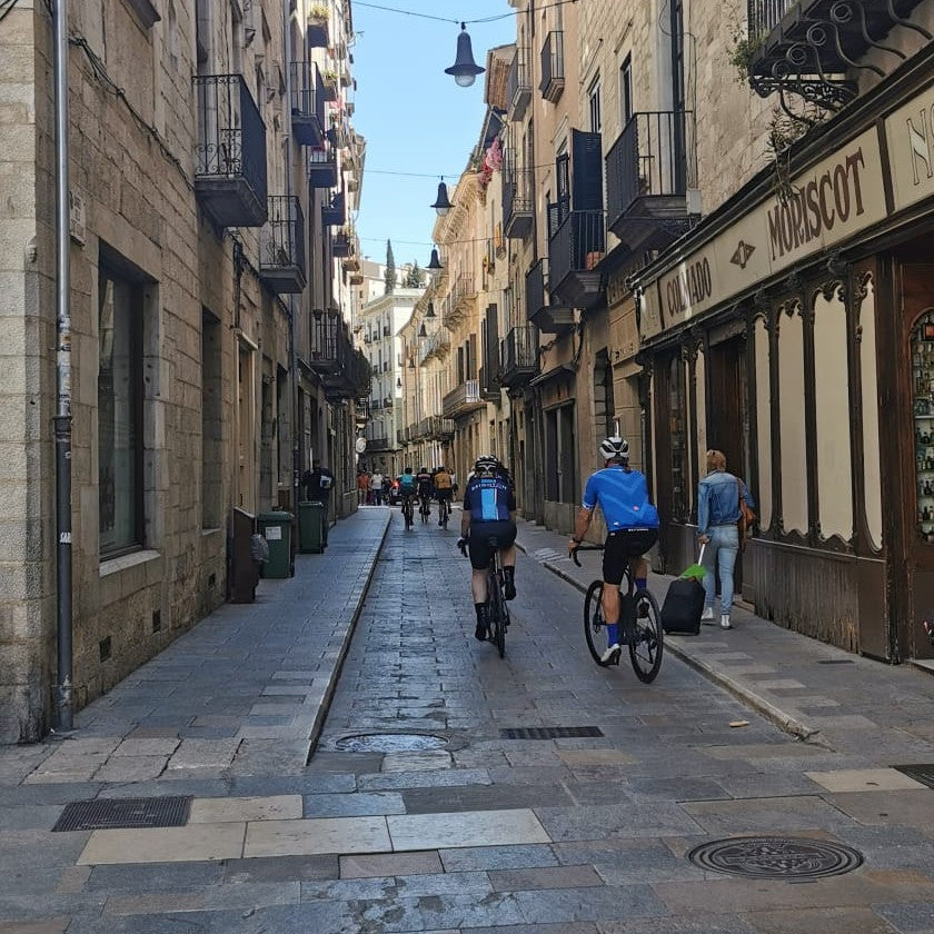 two cyclists riding down a stone alley way