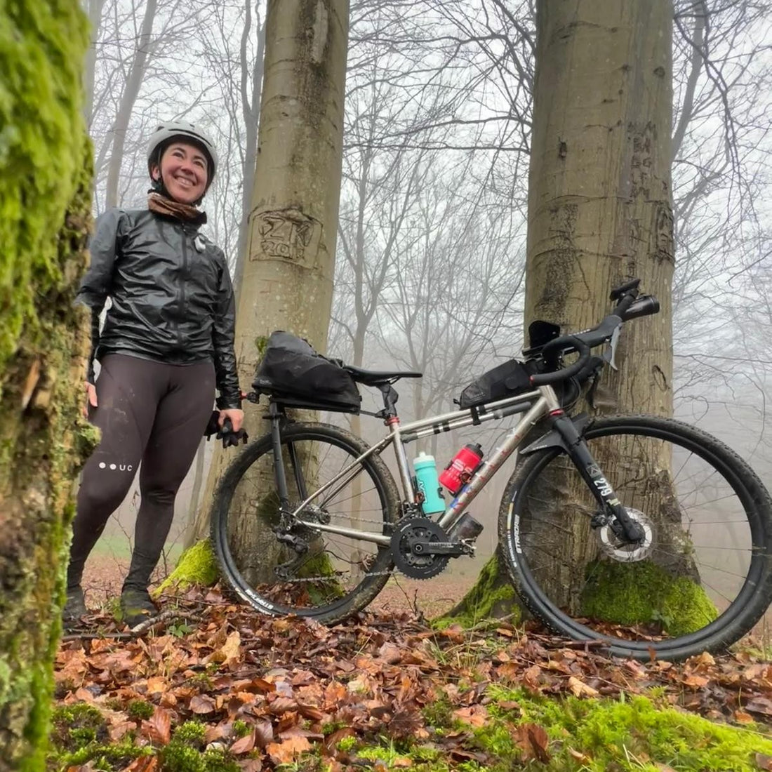 A woman by her bike in woods.