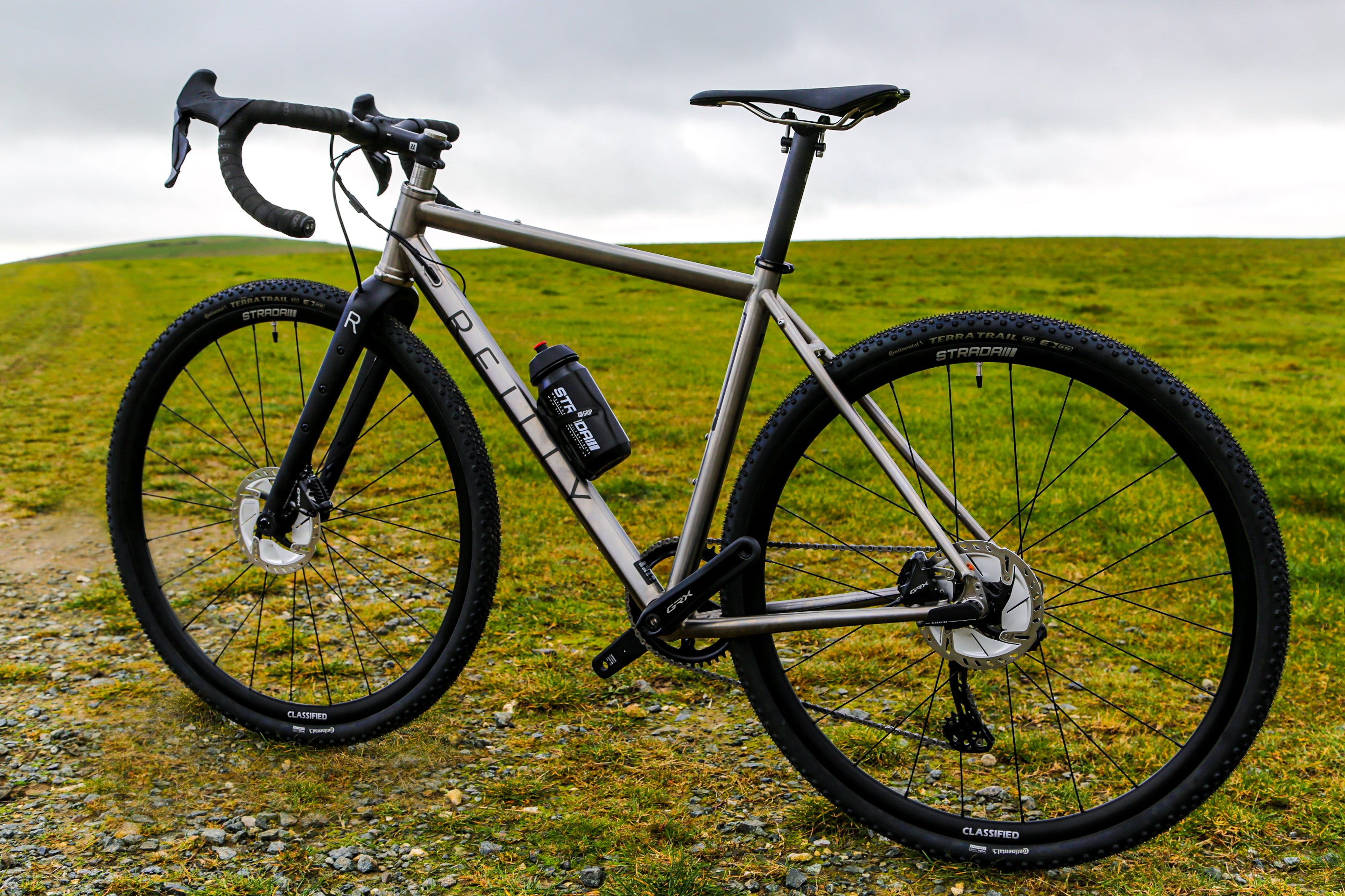 A Reilly bike proped up againt a green landscape.
