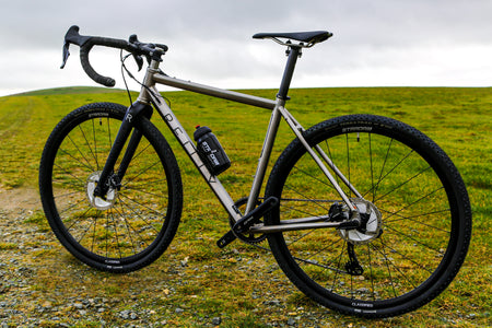 A Reilly bike proped up againt a green landscape.